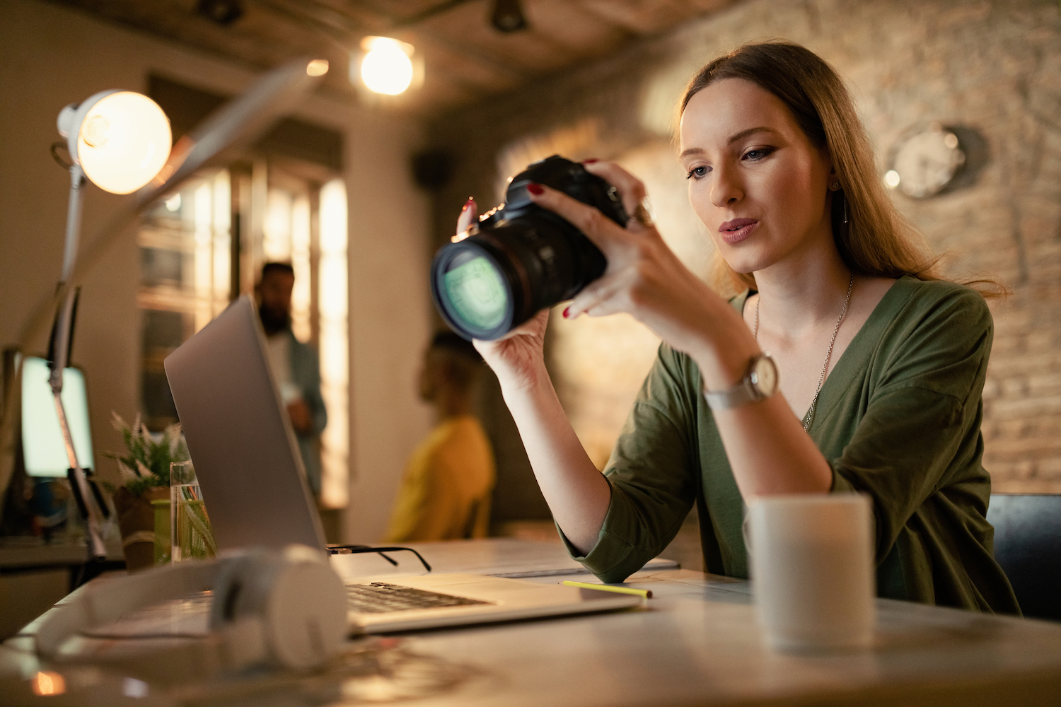 low-angle-view-female-photographer-looking-photos-camera-while-working-late-office